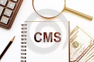 CMS Content Management System with text on notepad and office accessories on white desk