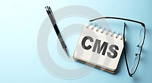 CMS text written on a notepad on the blue background