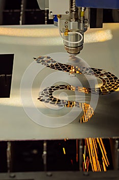 CNC laser cutting machine making holes in sheet metal with sparks