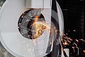 Cnc laser cutting machine working with cylindrical metal workpiece with sparks