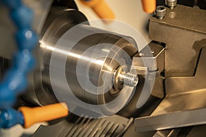 The CNC lathe machine in metal working process cutting the screw parts with the cutting tools.