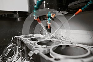 CNC milling machine cutting aluminium automotive part with a coolant liquid. Hi-Technology manufacturing process.