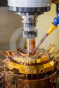 The CNC milling machine cutting the tire mold parts with liquid oil coolant method in vertical scene.