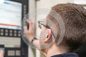 The operator of the CNC milling machine writes the program and makes adjustments for machining parts by cutting.