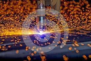 CNC Plasma torch cutting steelplate with orange bokeh sparks