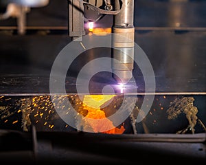 CNC Plasma torch cutting steelplate with red sparks