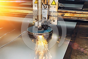 CNC programmable laser plasma cutting machine cuts sheet of metal with sparks