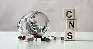 CNS - acronym on cubes on a light background with a capacity with tablets photo