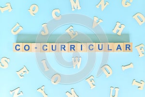 Co-curricular activities concept. Wooden blocks word typography flat lay in blue background.