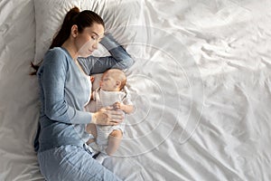 Co-sleeping with baby. Young woman napping in bed with her newborn child