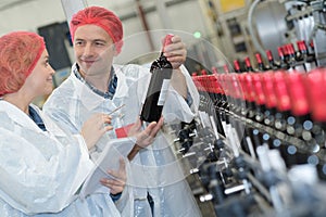 Co-worker showing newly produced bottle wine on winery manufactory