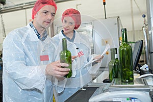 co-workers examining bottles at bottling plant