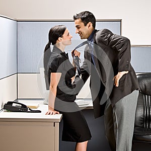 Co-workers kissing in office cubicle