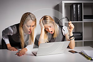 Co-workers looking at computer in shock