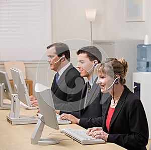 Co-workers working at computers in call center