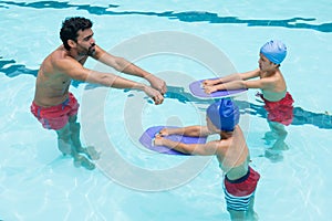 Coach assisting a kids in swimming in pool