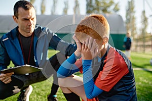 Coach comforting crying little soccer player after missed goal
