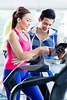 Coach evaluating performance of woman on treadmill