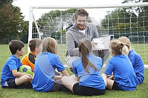 Coach Giving Team Talk To Elementary School Soccer Team