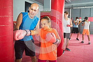 Coach helps the girl to correctly beat the punching bag