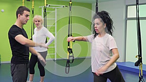 Coach helps young woman to squat correctly in the gym