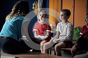 Coach talking with boy with broken arm wrapped medical cast plaster in locker room