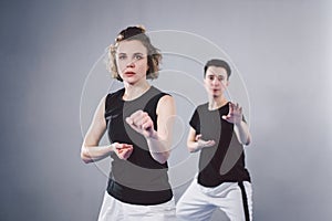 Coach teaches athlete to hit kick. Strong female martial arts athletes in their taekwon-do training. Two young women instructor