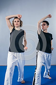 Coach teaches athlete to hit kick. Strong female martial arts athletes in their taekwon-do training. Two young women instructor