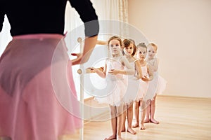 Coach teaches children. Little ballerinas preparing for performance by practicing dance moves