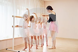 Coach teaches children. Little ballerinas preparing for performance by practicing dance moves