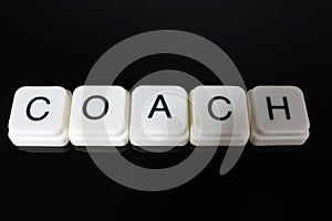 Coach text word title caption label cover backdrop background. Alphabet letter toy blocks on black reflective background. White al