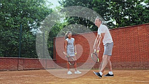 Coacher showing to the girl how to serve the ball