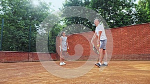 Coacher showing to the girl how to serve the ball