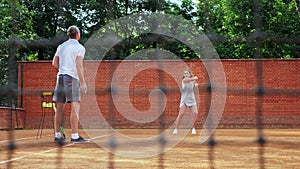 Coacher teaching young girl to playing tennis.