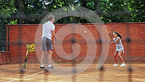 Coacher teaching young girl to playing tennis.