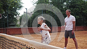 Coacher teaching young girl to playing tennis.