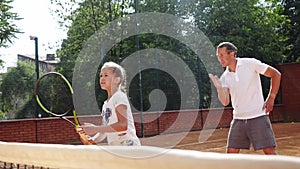 Coacher teaching young girl to playing tennis.