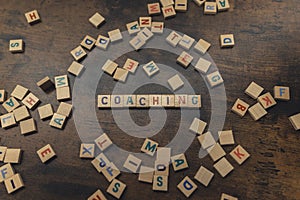 Coaching - concept word wooden alphabet letters text on the dark wood background