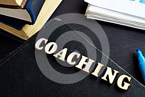 Coaching from wooden letters on a book. Mentoring