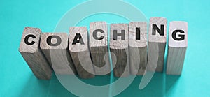 Coaching word on wooden blocks on aqua blue background. Personal and business achievements concept