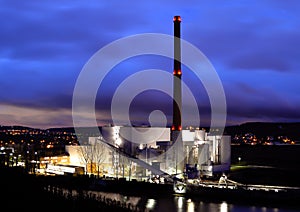 Coal-fired power plant at night with cloudy sky