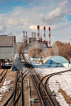 Coal-fired thermal power plant with smoke from pipes on a sunny day.