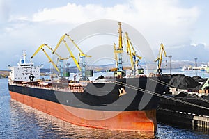 Coal is loaded into the holds of a dry cargo ship in the seaport 24 hours a day.