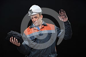 Coal miner showing lump of coal with thumbs up