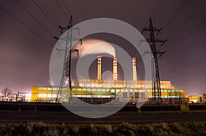 Coal power plant with chimneys and power line at night