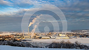 Coal power plant with smoking chimneys and solar panels in winter