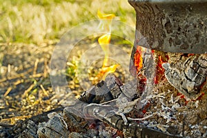 Coals in a metal barrel on backyard. Smoldering fire in a round metal barrel after burning dry branches.