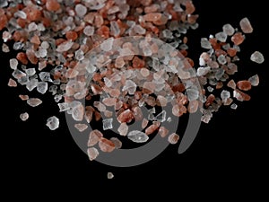 Coarse pink himalayan salt crystals isolated on black background close up