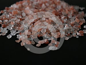 Coarse pink himalayan salt crystals isolated on black background close up