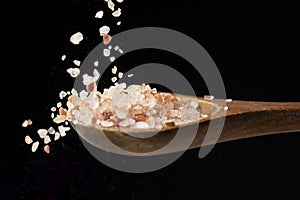 Coarse pink salt falling on wooden spoon